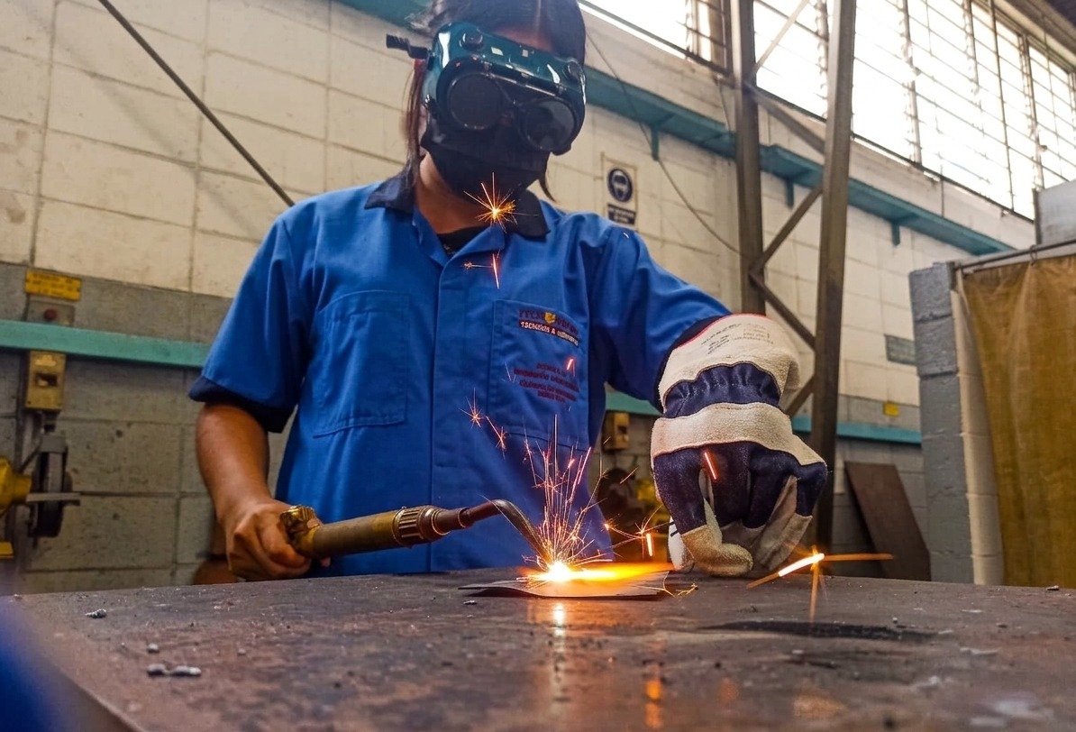 Becaria soldando metal en taller